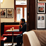 **

A person subtly observing their surroundings in a bustling Istanbul café. Focus on details like overhearing conversations, noticing posters on the wall, or a newspaper headline catching their eye. The overall mood is one of quiet observation and potential discovery in the everyday.

**